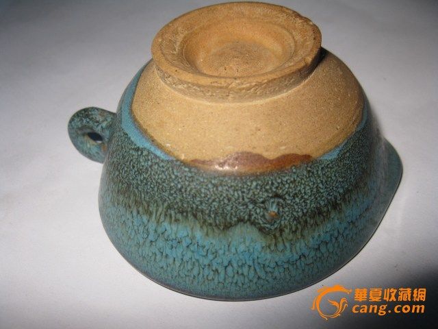 钧瓷酒盏规格:口径:8.4厘米 高:4.3厘米特征:胎质较粗松,呈灰白色积釉肥厚,浑浊失透,多棕眼,釉泡,光泽较差。施釉不到底,圈足宽厚外撇,内外无釉,足内胎面留有尖状痕迹。 从造型上看,属于日常生活用具,饮酒、饮茶、盛物、敬神、祭神、祭祖等物质生活和精神生活方面的使用。